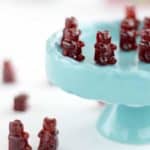 cherry gummy bears sitting on a cupcake stand and on a table