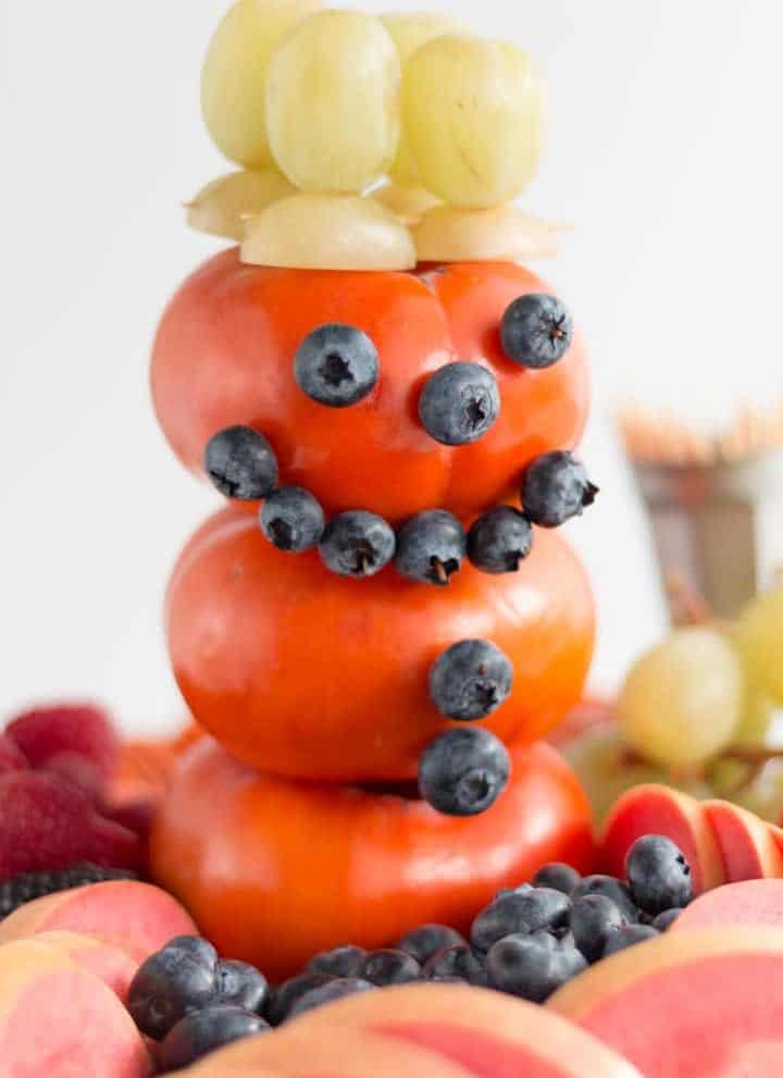 snowman made of persimmon, blueberries, green grapes